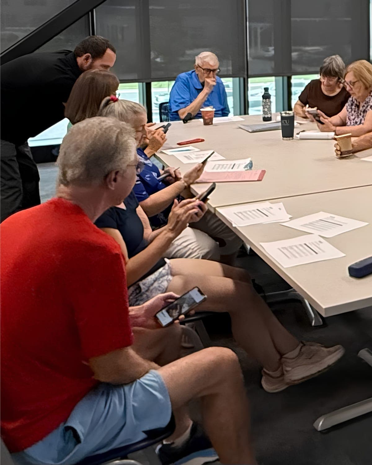 A GOLD trainer leaning in to help members work through a task on their phones