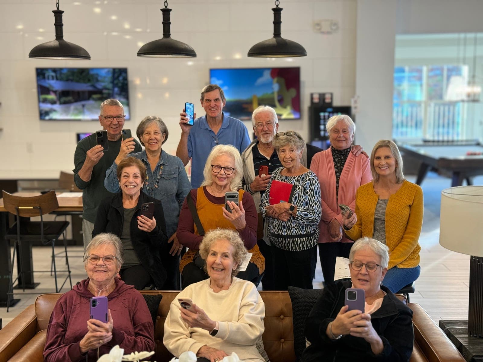 Twelve GOLD members holding up their phones and smiling at the end of a workshop